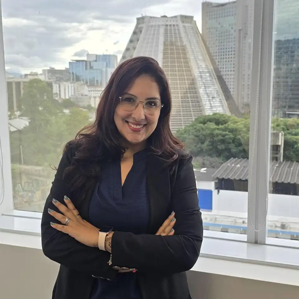 Marianna standing at an office window with high buildings in the background